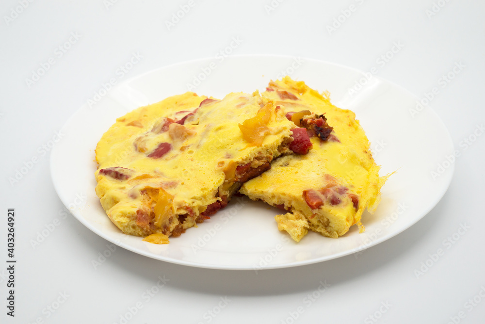Closeup of homemade omelette pieces with peppers in a white plate Closeup of homemade omelette pieces with peppers in a white plate
