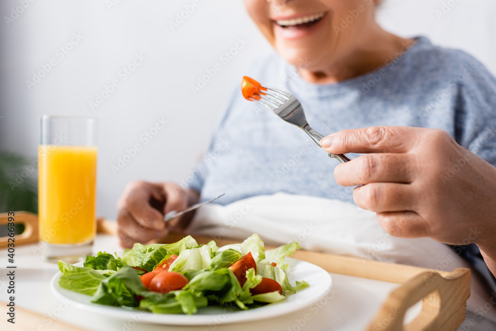 cropped view of joyful woman having breakfast in hospital, blurred background cropped view of joyful woman having breakfast in hospital, blurred background