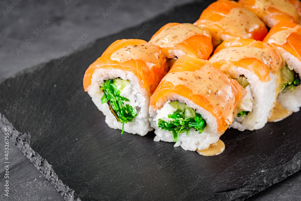 appetizing sushi roll philadelphia with salmon cucumber and chuka on a black stone plate appetizing sushi roll philadelphia with salmon cucumber and chuka on a black stone plate