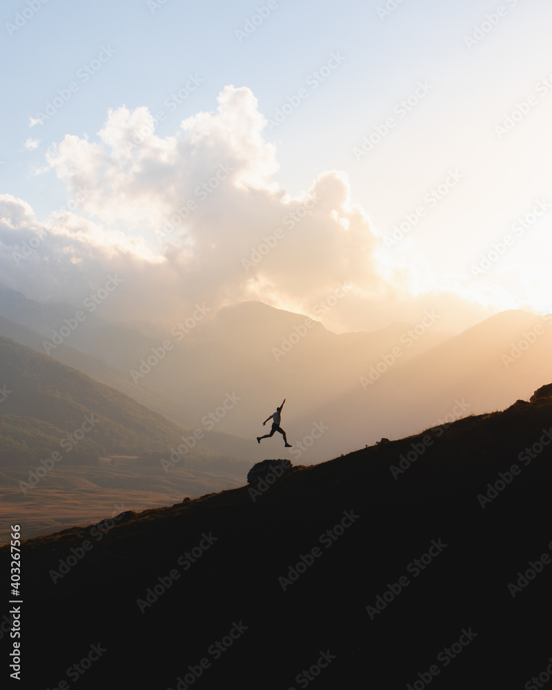 Silhouette of a man jumping at sunset in the mountains 