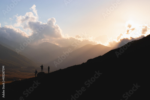 Silhouette of three men at sunset in the mountains 