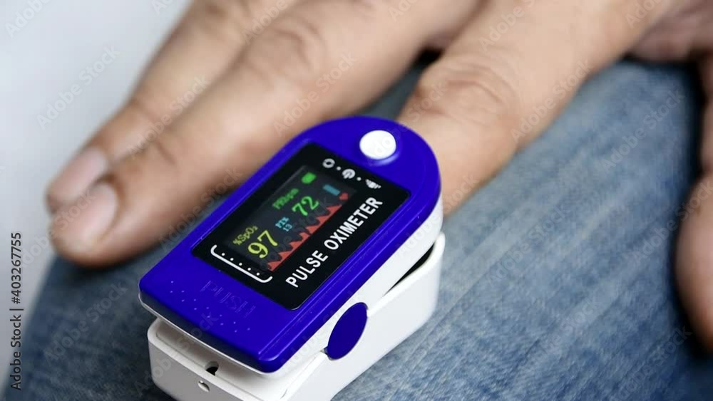 A man put on a pulse oximeter on his finger and checks his heart rate and the amount of oxygen in his blood. A man put on a pulse oximeter on his finger and checks his heart rate and the amount of oxygen in his blood.