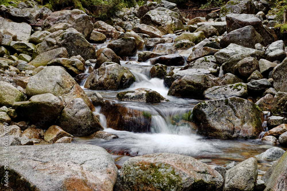 Water flowing in rocks in wild mountains river. Waksmundzki stream raging in High Tatras Mountains in Poland.