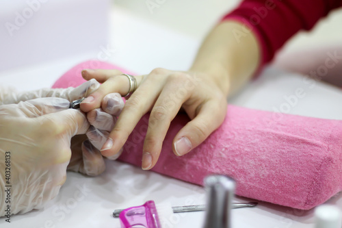 Closeup shot of a woman in a nail salon receiving a manicure by a beautician with nail file. Woman getting nail manicure. Beautician file nails to a customer