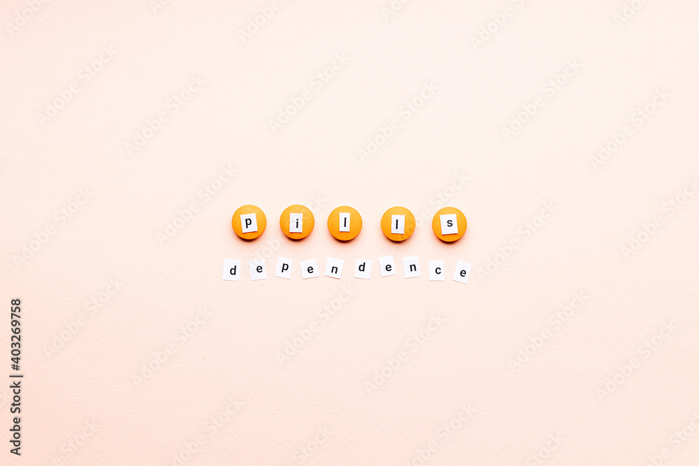Obraz premium words pills dependence on orange pills over pink background. creative medicine and drug concept. pharmacy conceptual. above view