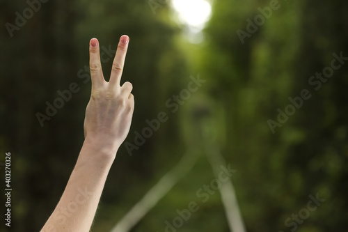 Hand with two fingers up in the peace or sign for symbol of peace or victory on natural background. woman shows number two with two fingers. © Andriy Medvediuk