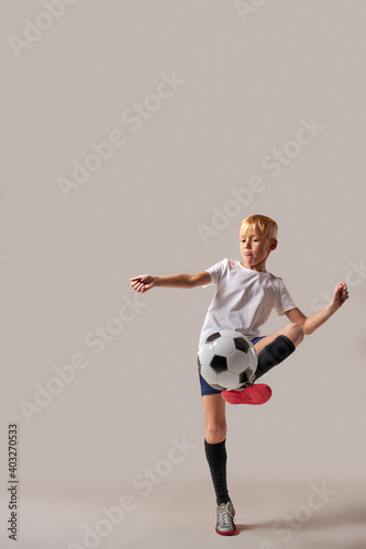 Fototapeta Naklejka Na Ścianę i Meble -  soccer player boy kicking playing with ball, wearing sportive uniform, try to learn more football tricks