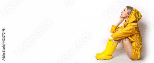Foto Horizontal banner with young woman in illuminating yellow slicker and rubber boots