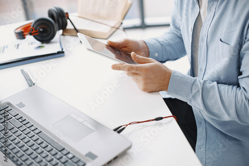 Man sitting in living room at home. Guy enjoying studying using laptop and headset. Man use a tablet. photo