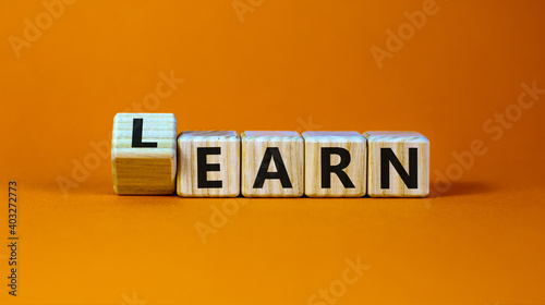 Learn or earn symbol. Turned a cube and changed the word 'earn' to 'learn'. Beautiful orange background. Business and learn or earn concept. Copy space. photo