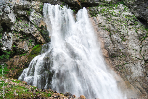 Mountain waterfall. A powerful mountain river bursts out of a mountain crevice and falls like a waterfall. Mountain river. A huge waterfall. The Gega waterfall photo