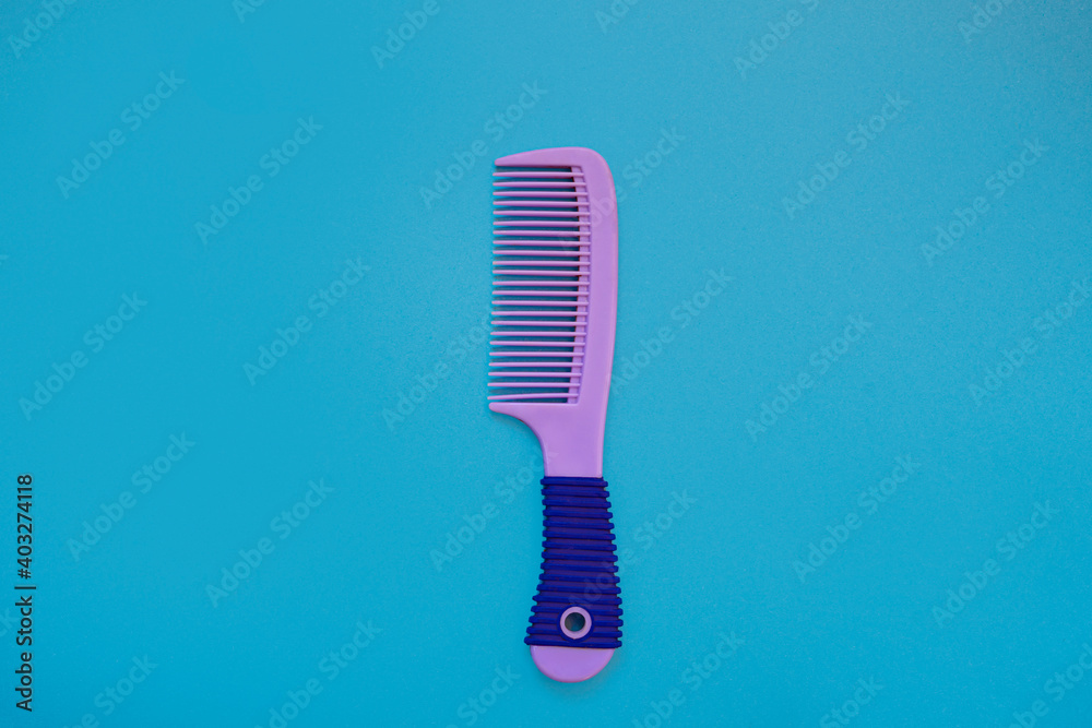 Beautiful female purple hairbrush on a blue background. Hair care concept. top view. copy space. Flat lay