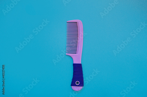 Beautiful female purple hairbrush on a blue background. Hair care concept. top view. copy space. Flat lay