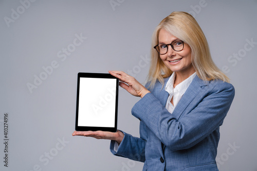 50s caucasian office lady in formal attire holding a tablet isolated over grey background