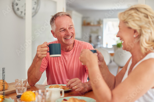 Fotografie Retired Couple At Home In Kitchen Eating Breakfast Together