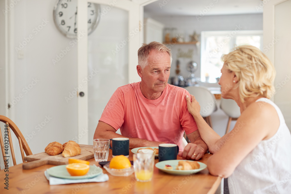 Senior Woman Comforting Man Suffering With Depression At Breakfast Table At Home
