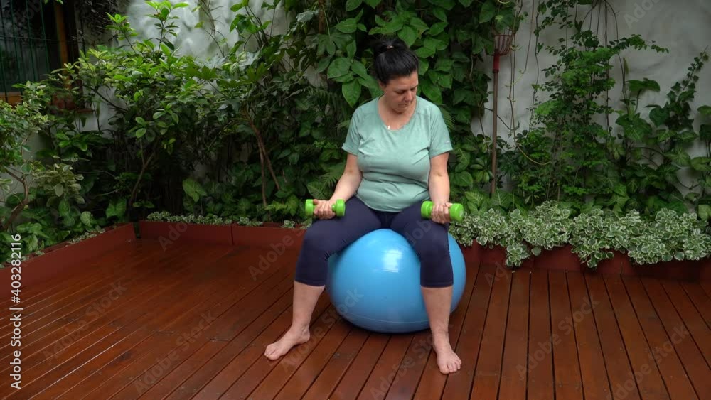 Mujer de mediana edad haciendo ejercicio con pelota en el jardín de su casa
