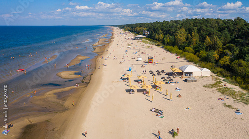 Dzintari, Jurmala ,Latvia, Baltics. Aerial view photo from flying drone panoramic to Dzintari sandy beach full of people sunbathing and swimming in the Baltic Sea on a hot and sunny summer day. (Serie