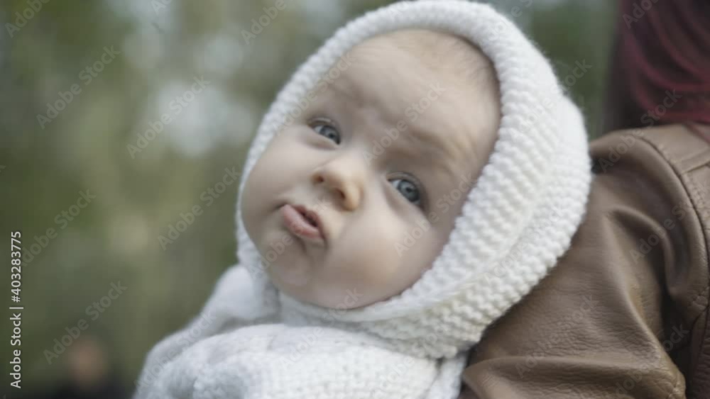 Close-up of charming little boy with grey eyes on woman's hands looking at camera. Portrait of cute Caucasian infant child outdoors with mother. Beauty and childhood concept. Close-up of charming little boy with grey eyes on woman's hands looking at camera. Portrait of cute Caucasian infant child outdoors with mother. Beauty and childhood concept.