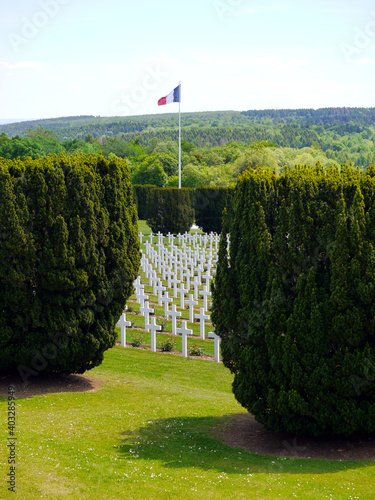 Weisse Kreuze mit einer französischen Flagge im Hintergrund auf dem Soldatenfriedhof von Douaumont in Frankreich photo