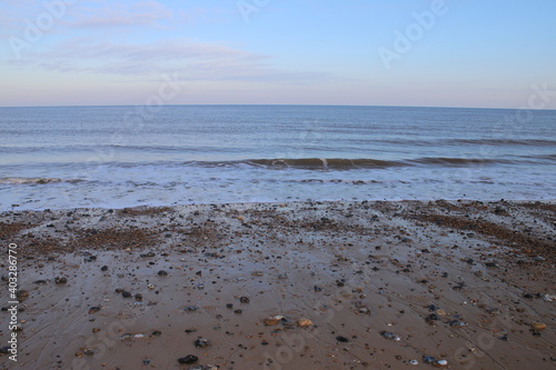 Fotografia Beautiful landscape view out across ocean waves towards sea horizon on sandy bea