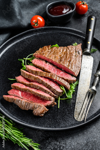 Grilled and cut Flat Iron steak. Marble beef meat. Black background. Top view