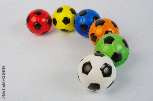 Multi-colored toy soccer balls on a light background.