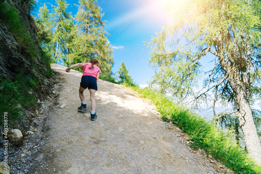 Obraz premium Children hiking on beautiful summer day in alps mountains Austria, resting on rock and admire amazing view to mountain peaks. Active family vacation leisure with kids. Outdoor fun and healthy activity