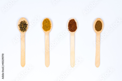 Various spice seeds in wooden spoons on a white background. Seeds of beet, mustard, lettuce, arugula, on a white background. Place for an inscription. View from above.
