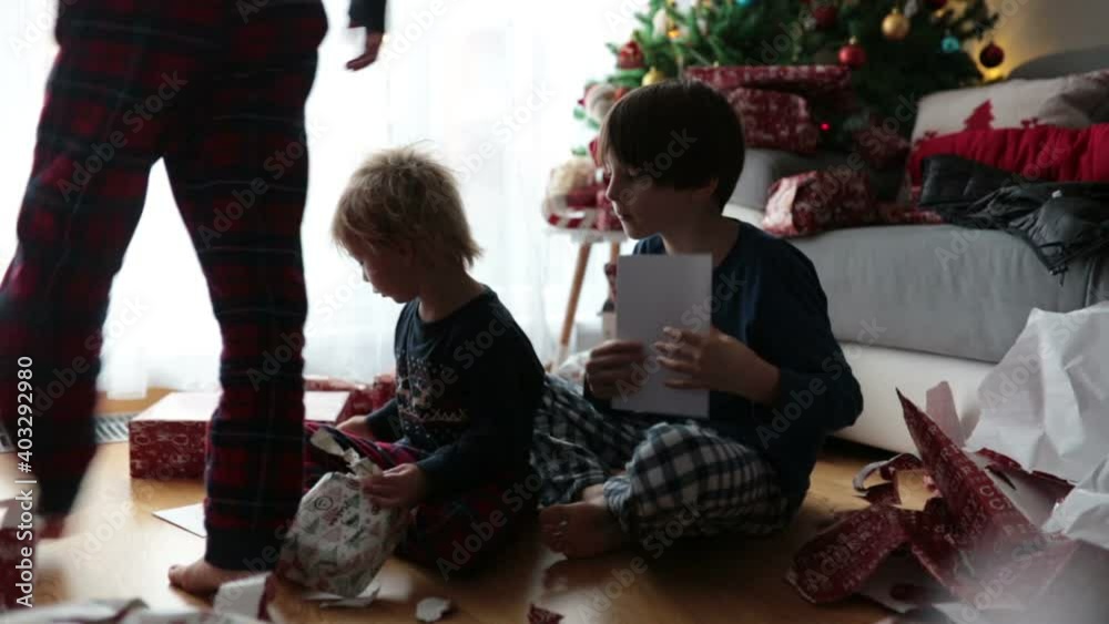Happy children in pajamas on Christmas morning opening presents at home, excited Happy children in pajamas on Christmas morning opening presents at home, excited