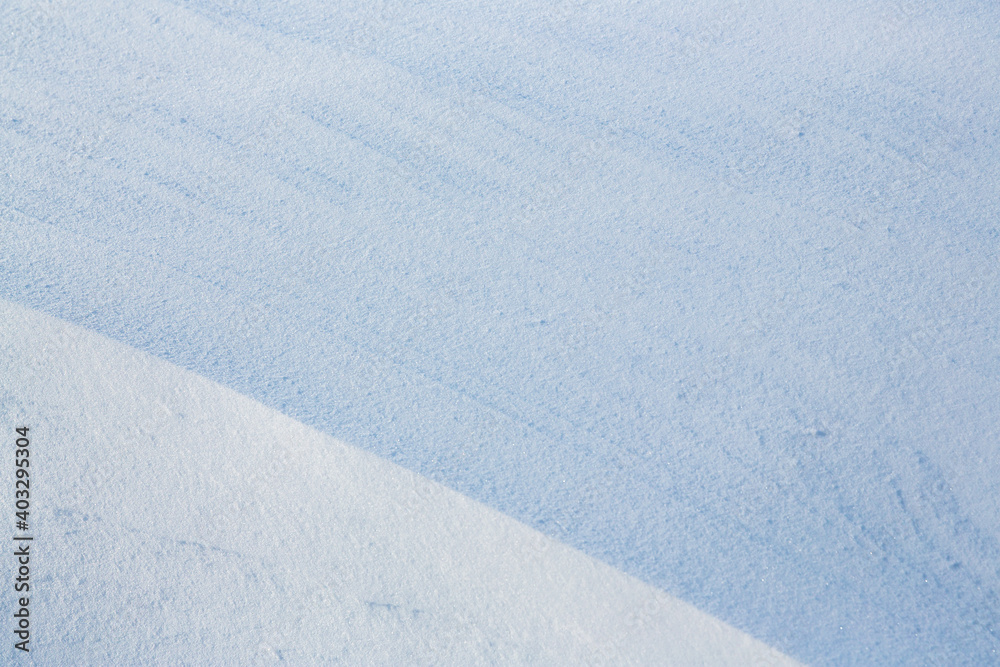 Beautiful winter background with snowy ground. Natural snow texture. Wind sculpted patterns on snow surface.