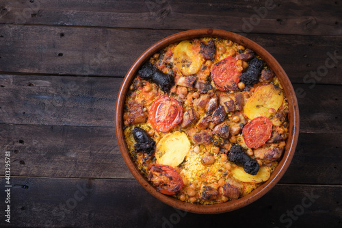 clay pot of baked rice with tomato, potato and black pudding