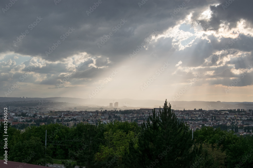Obraz premium The evening sun shines on the city through the thick clouds (Brno, Czech republic)