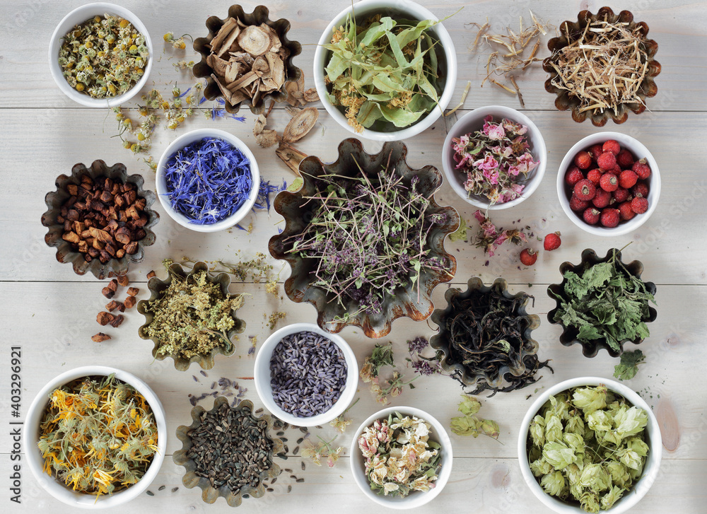 Assortment of dried herbs: blossom, root and seed, flat on the table, lavender, chamomile, lime, rose, cornflower, meadowsweet, thyme and others overhead top view, naturopathy and medicine concept