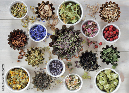 Assortment of dried herbs: blossom, root and seed, flat on the table, lavender, chamomile, lime, rose, cornflower, meadowsweet, thyme and others overhead top view, naturopathy and medicine concept