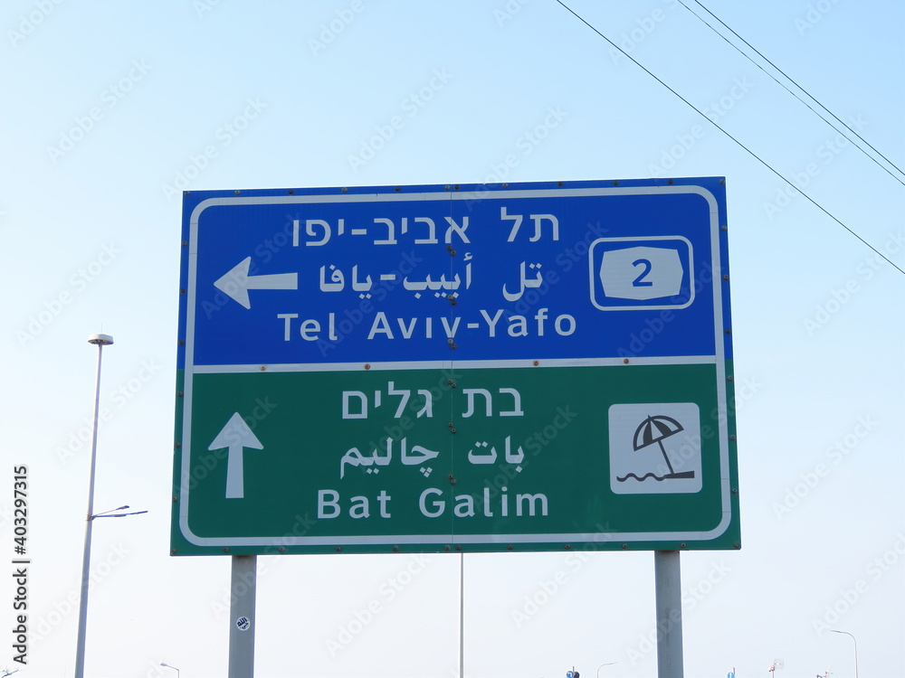 Road signs with the inscriptions Tel Aviv-Yafo and Bat Galim beach in three languages (English, Arabic, and Hebrew) close-up in Haifa, Israel.