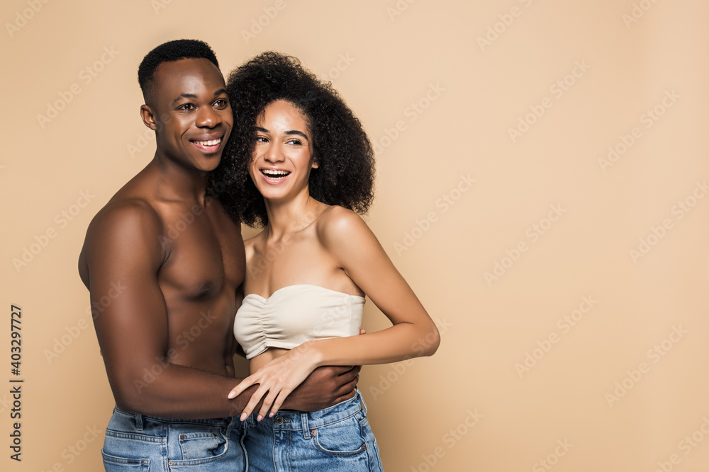 happy african american woman laughing and hugging with cheerful boyfriend isolated on beige happy african american woman laughing and hugging with cheerful boyfriend isolated on beige