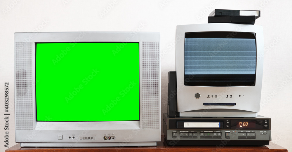 Old silver green screen TV for video and photos with built-in DVD player and a vintage video recorder from the 1980s, 1990s, 2000s next to it. Old silver green screen TV for video and photos with built-in DVD player and a vintage video recorder from the 1980s, 1990s, 2000s next to it.
