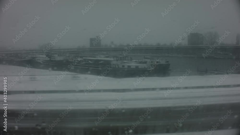 still shot riding in a vehicle in winter raining day over a wet rainy window and snow outside on a high way during the dark gloomy cold day with urban city factory vessel landscape in the background still shot riding in a vehicle in winter raining day over a wet rainy window and snow outside on a high way during the dark gloomy cold day with urban city factory vessel landscape in the background