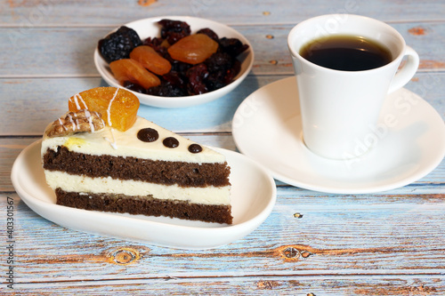 a slice of delicious cake, dried fruits and a cup of coffee on the table