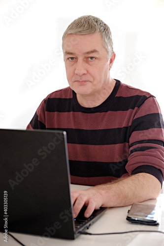 portrait of caucasian man 45 years old working with laptop online, computer, isolated, white background, mobile on table, office worker