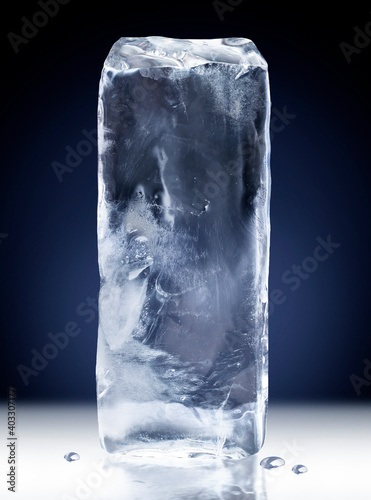 Vertical rectangular block of ice isolated on dark blue background with clipping path.