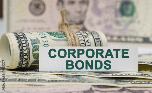 On the table are bills, a bundle of dollars and a sign on which it is written - CORPORATE BONDS