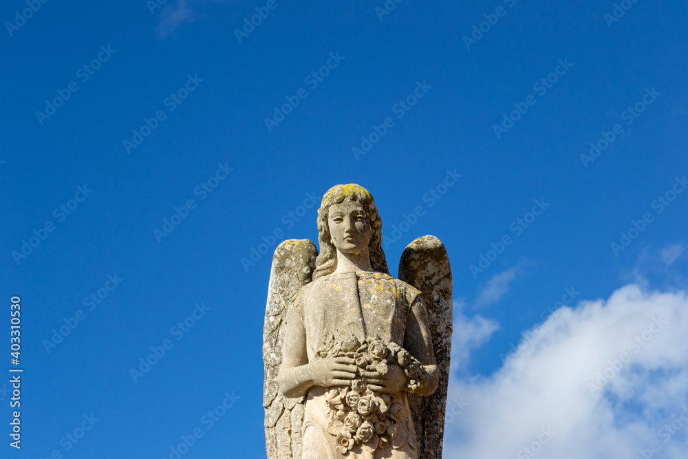 An old beautiful melancholic and delicate sculpture statue at the llucmajor cemetery in mallorca island balearic spain on a sunny clear day 