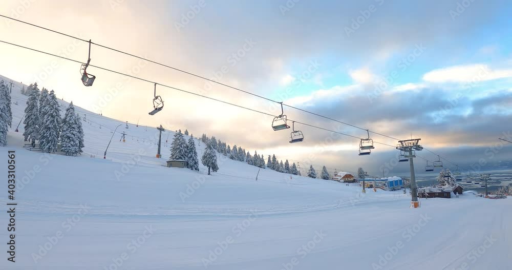 Elevated passenger ropeway for skiers. Empty chairlift on Krvavec ski resort, Slovenia. Onhill transport at ski area. Alps mountains slope under thick snow in winter season Elevated passenger ropeway for skiers. Empty chairlift on Krvavec ski resort, Slovenia. Onhill transport at ski area. Alps mountains slope under thick snow in winter season