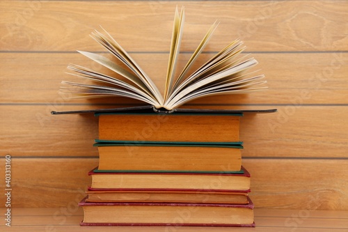Stack of books with opening book on wooden background. 