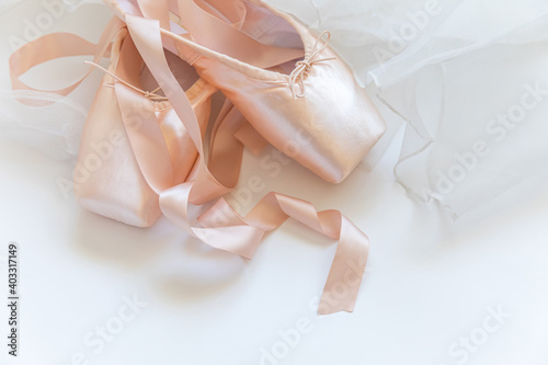 New pastel beige ballet shoes with satin ribbon and tutut skirt isolated on white background. Ballerina classical pointe shoes for dance training. Ballet school concept. Top view flat lay, copy space