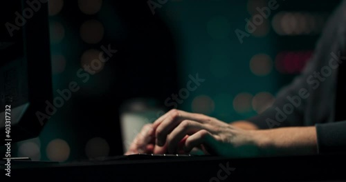 Close up of a young hackers hands writing malware on a computer keyboard in a secret hideout.