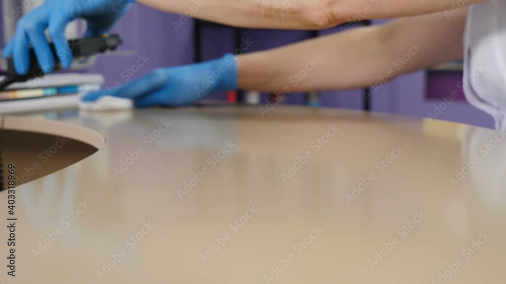 Cleaning in beauty salon or shop. Spraying and wiping reception surface. Client or patient care and protection. Person disinfecting table with sanitizer. Surface disinfection with cleaning agent. Hd Cleaning in beauty salon or shop. Spraying and wiping reception surface. Client or patient care and protection. Person disinfecting table with sanitizer. Surface disinfection with cleaning agent. Hd