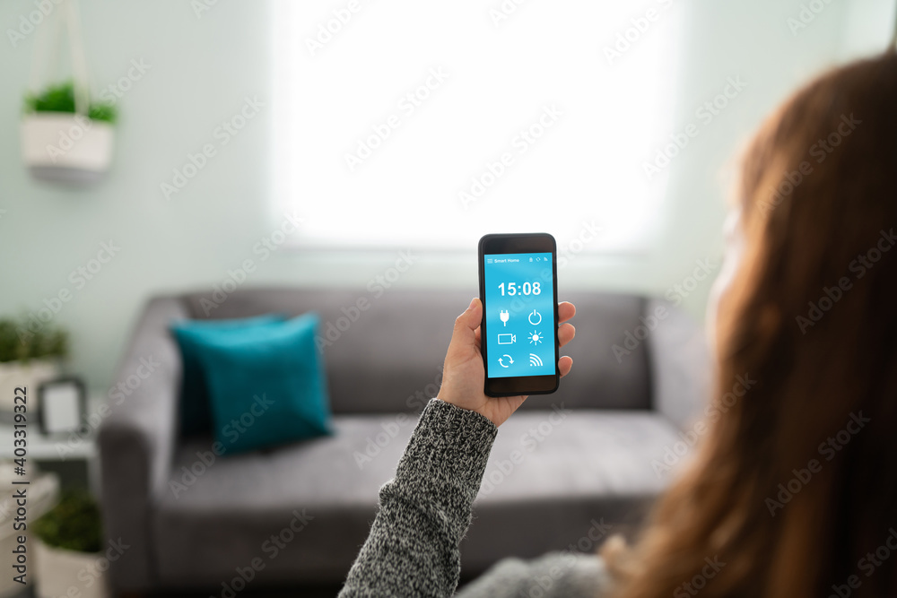 Woman seen from behind holding her smartphone in the lounge Woman seen from behind holding her smartphone in the lounge
